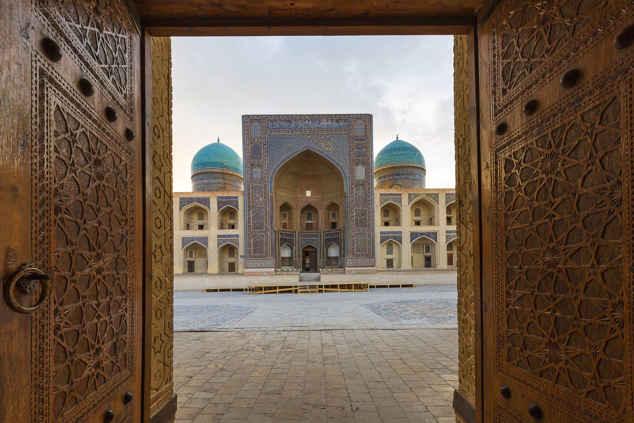 Blue domes of the Madressa through open wooden door in Bukhara, Uzbekistan.