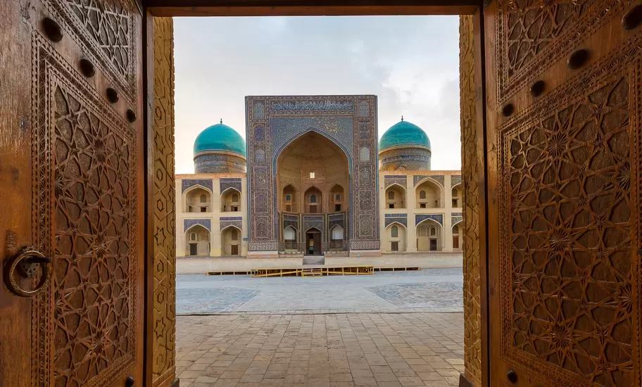 Blue domes of the Madressa through open wooden door in Bukhara, Uzbekistan.