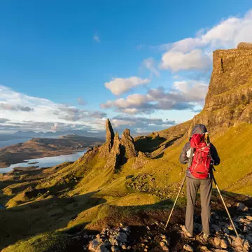 A hiker taking pictures near The Storr mountain peak on the Isle of Skye.