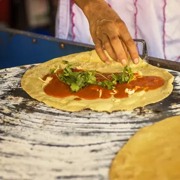 A chef's hand making a quesadilla with yellow mole (mole amarillo) from the Mexican state of Oaxaca