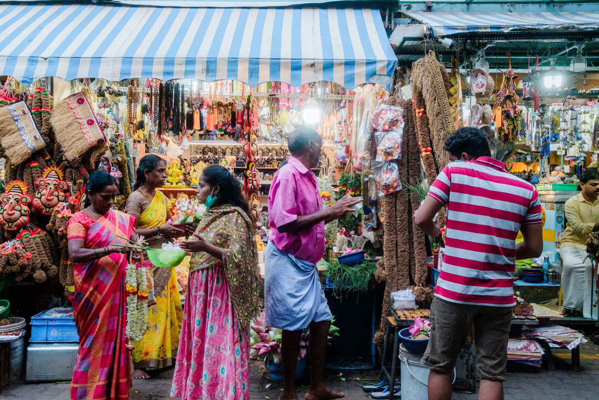 People in colorful shirts and saris gather at a market, where a variety of goods is for sale