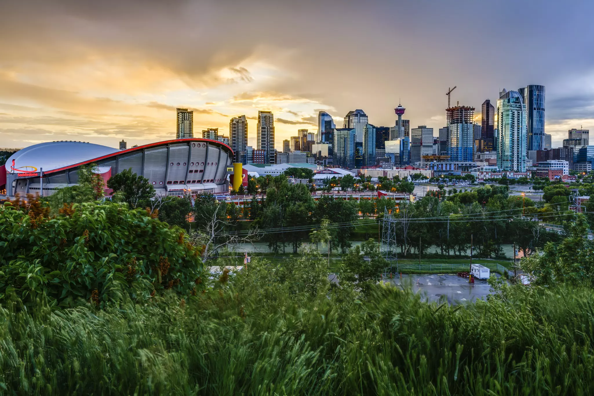 A city skyline complete with arena in the foreground is seen against a dramatic, stormy sky