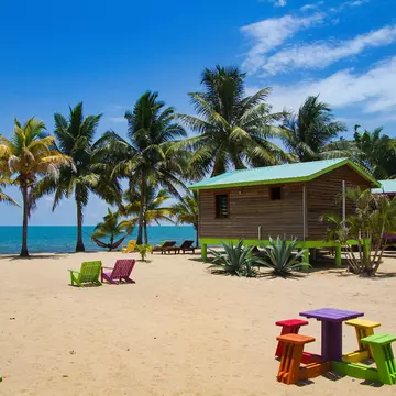 A wooden cabin on stilts on a sandy beach.