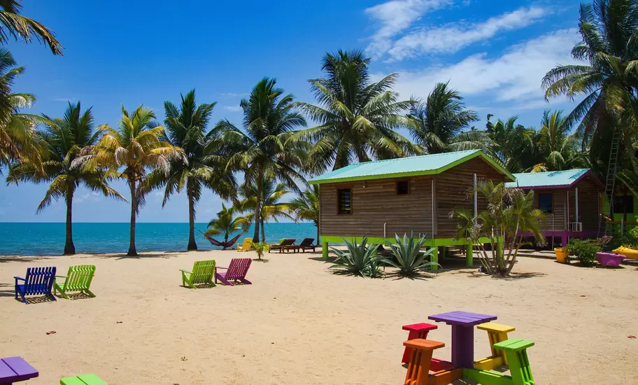 A wooden cabin on stilts on a sandy beach.