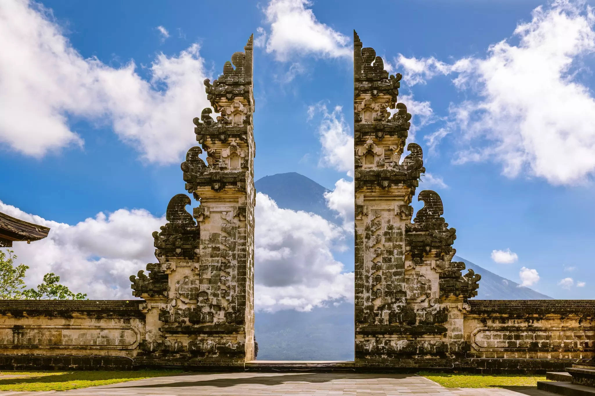 A carved stone gate frames a mountain in the background.