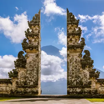A carved stone gate frames a mountain in the background.