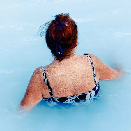 A woman relaxing in the waters of the Blue Lagoon in Reykjavik, Iceland