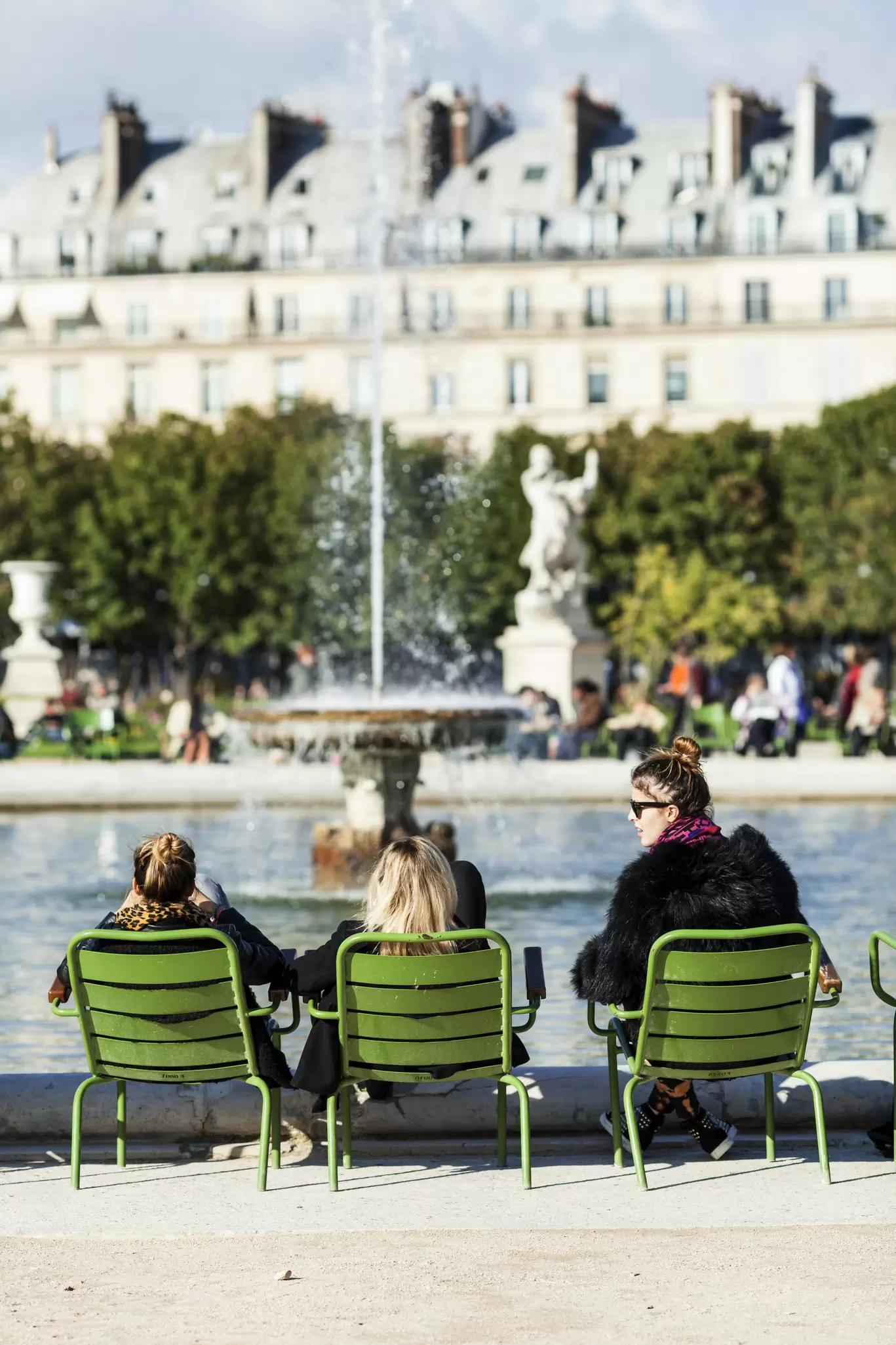 Three women sitting beside fountain in Paris.