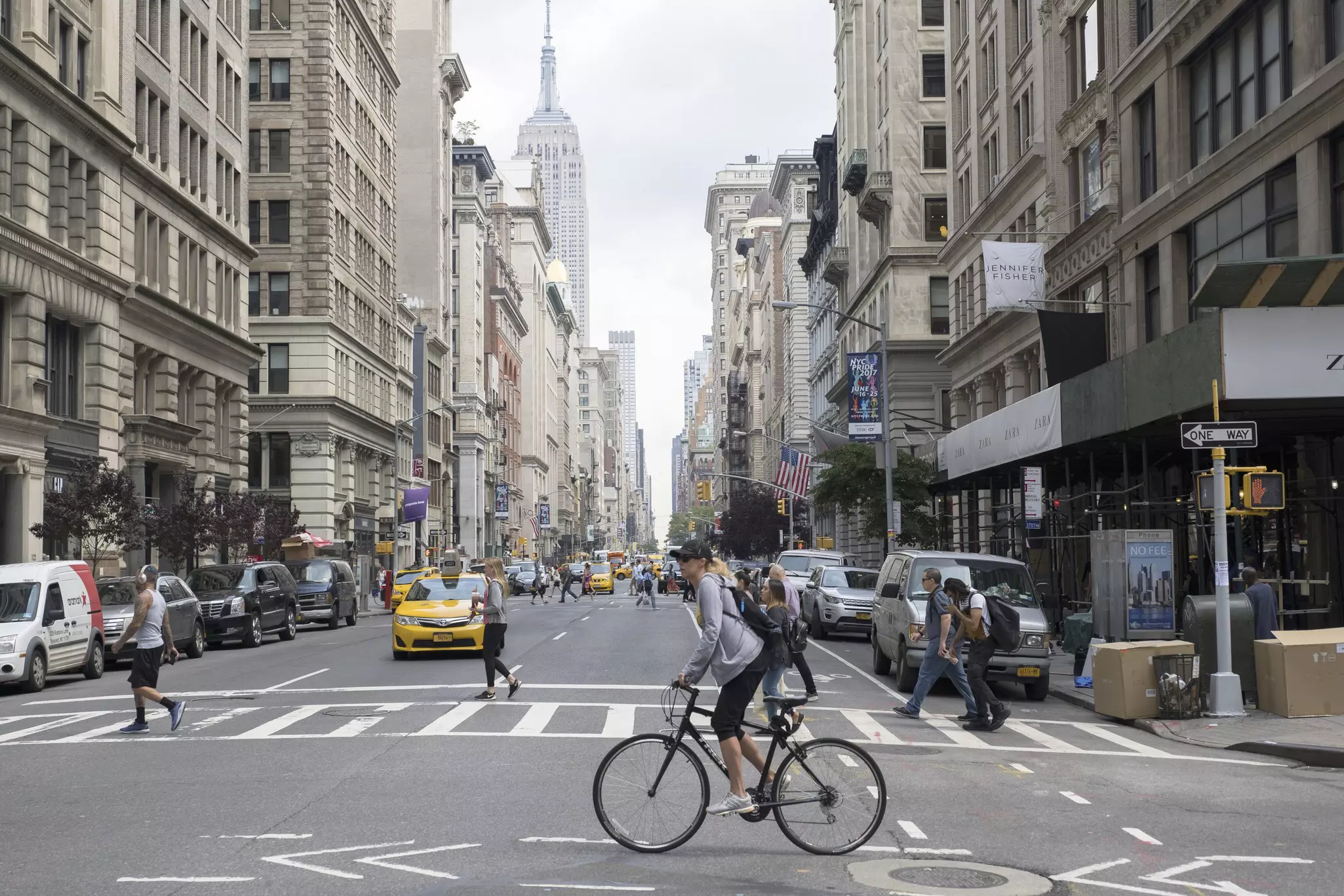 People crossing the street at Fifth Ave and 18th Street with a biker in the foreground and cars in the background.