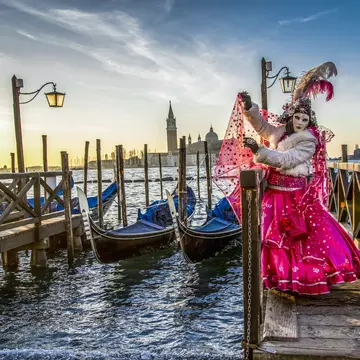 Venice naturally provides a dramatic backdrop for a festival goer in full costume. Vigen M / Shutterstock