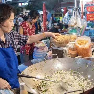 A chef prepares pad thai at the Yaowarat Night Market, Bangkok. amnat30/Shutterstock 
