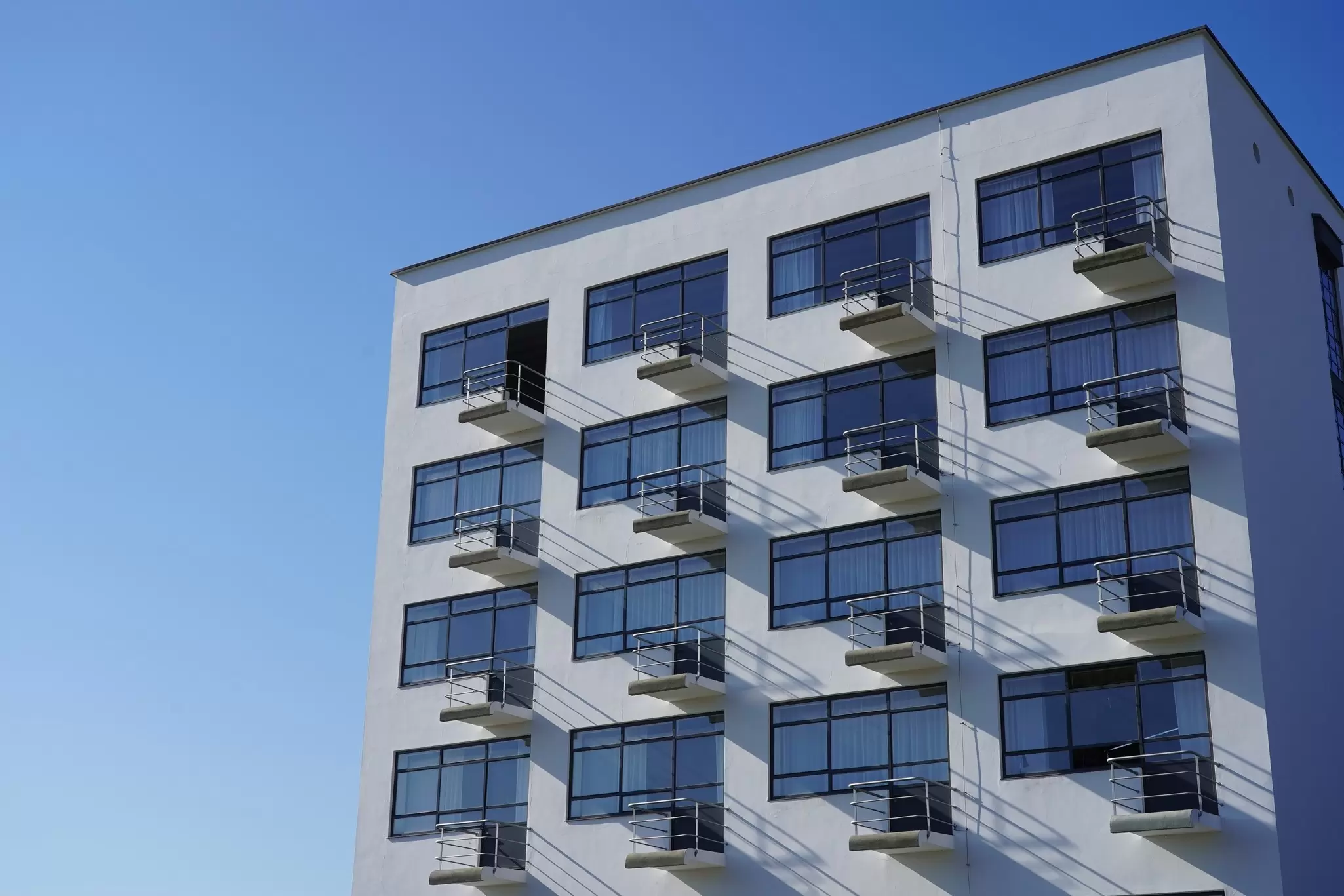 Close-up of a white apartment Bauhaus-Building designed by Walter Gropius in Dessau with a blue sky above