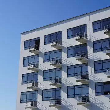 Close-up of a white apartment Bauhaus-Building designed by Walter Gropius in Dessau with a blue sky above