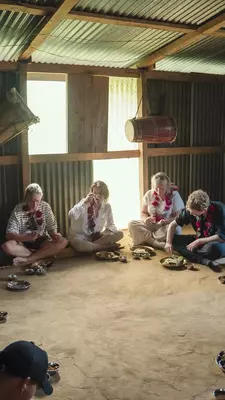 People seated on the floor eating from individual bowls.