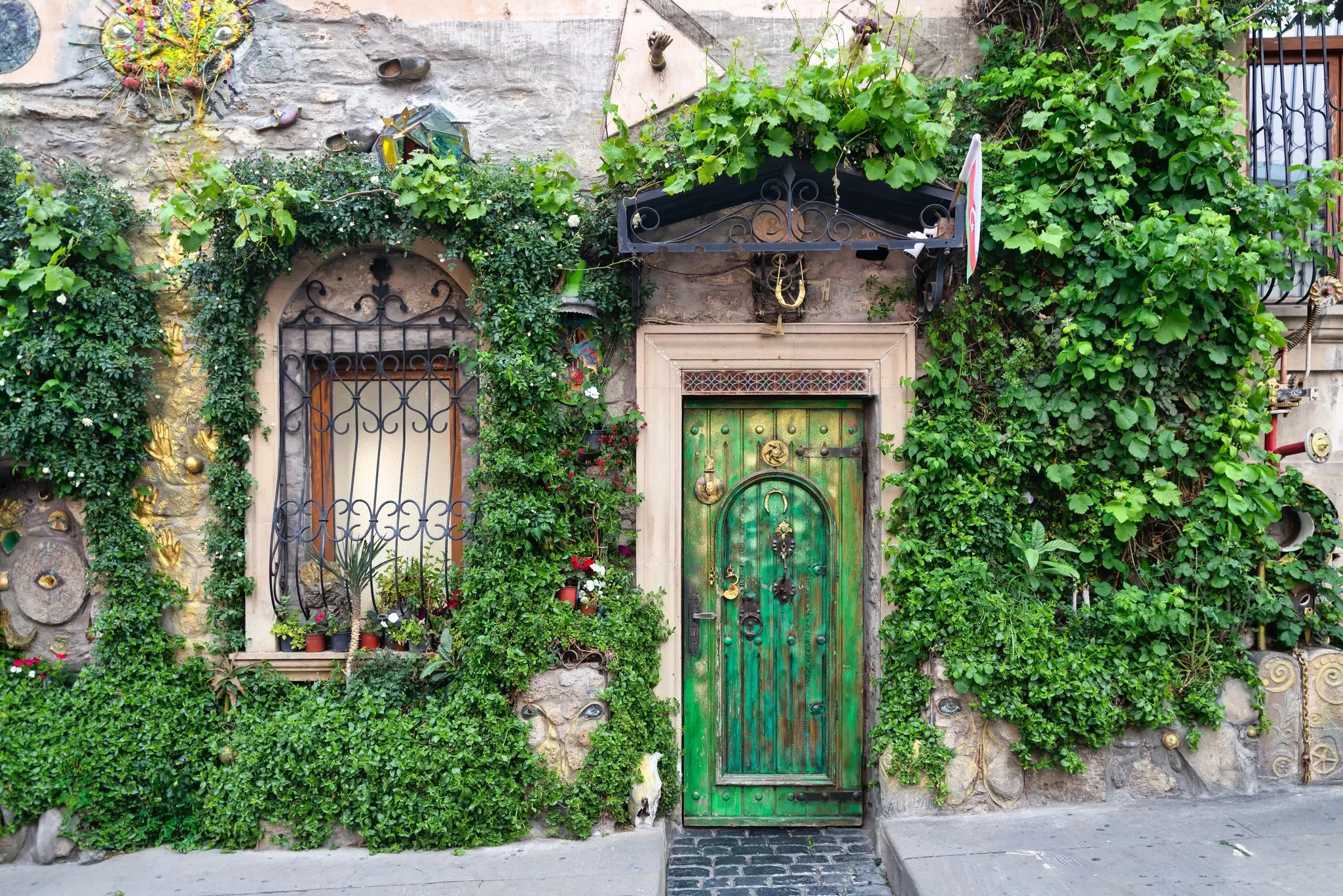 A striking green door framed by lush greenery and ornate windows enhances the historic beauty of Icherisheher, Baku.