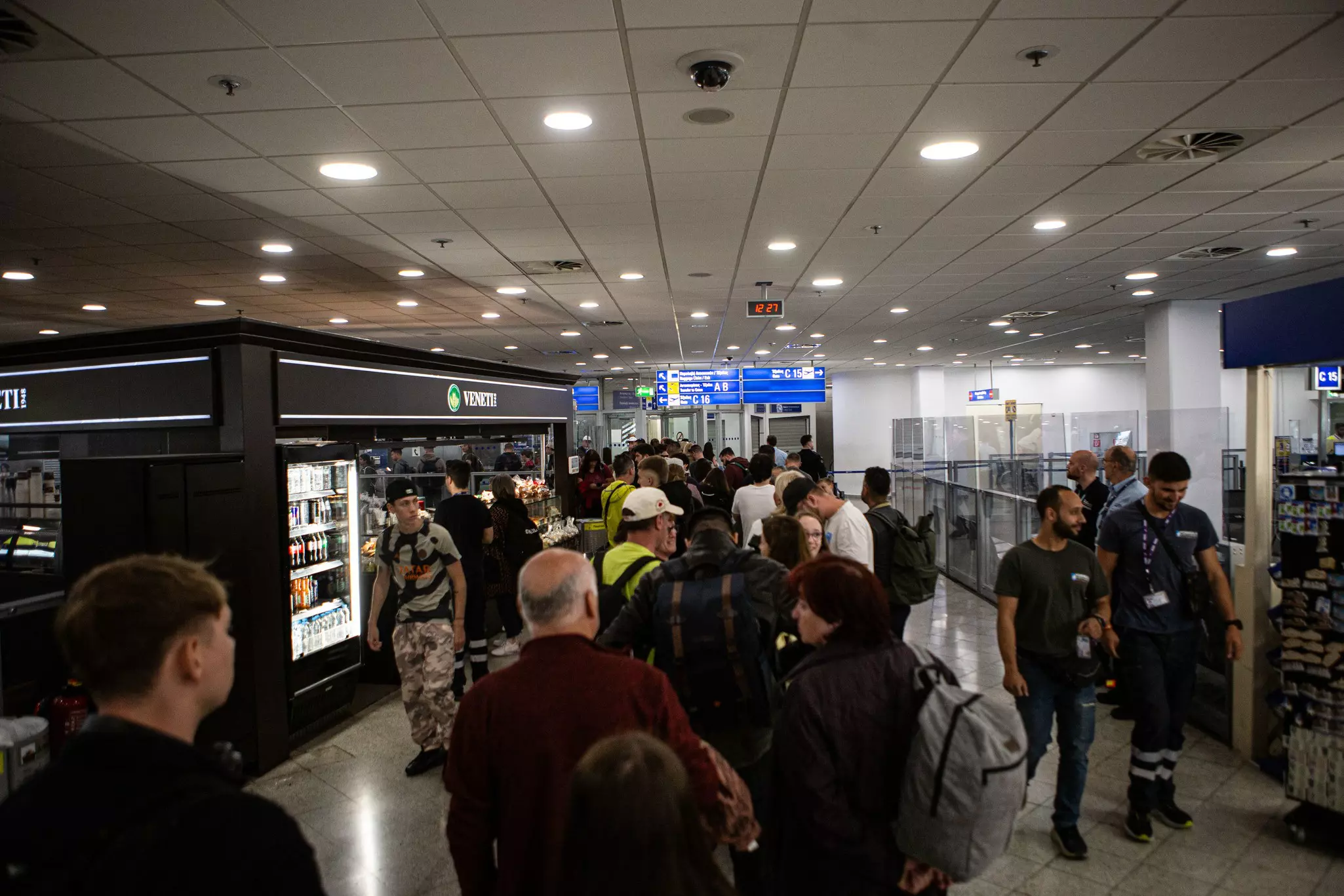 People line up in a narrow hallway of an airport.