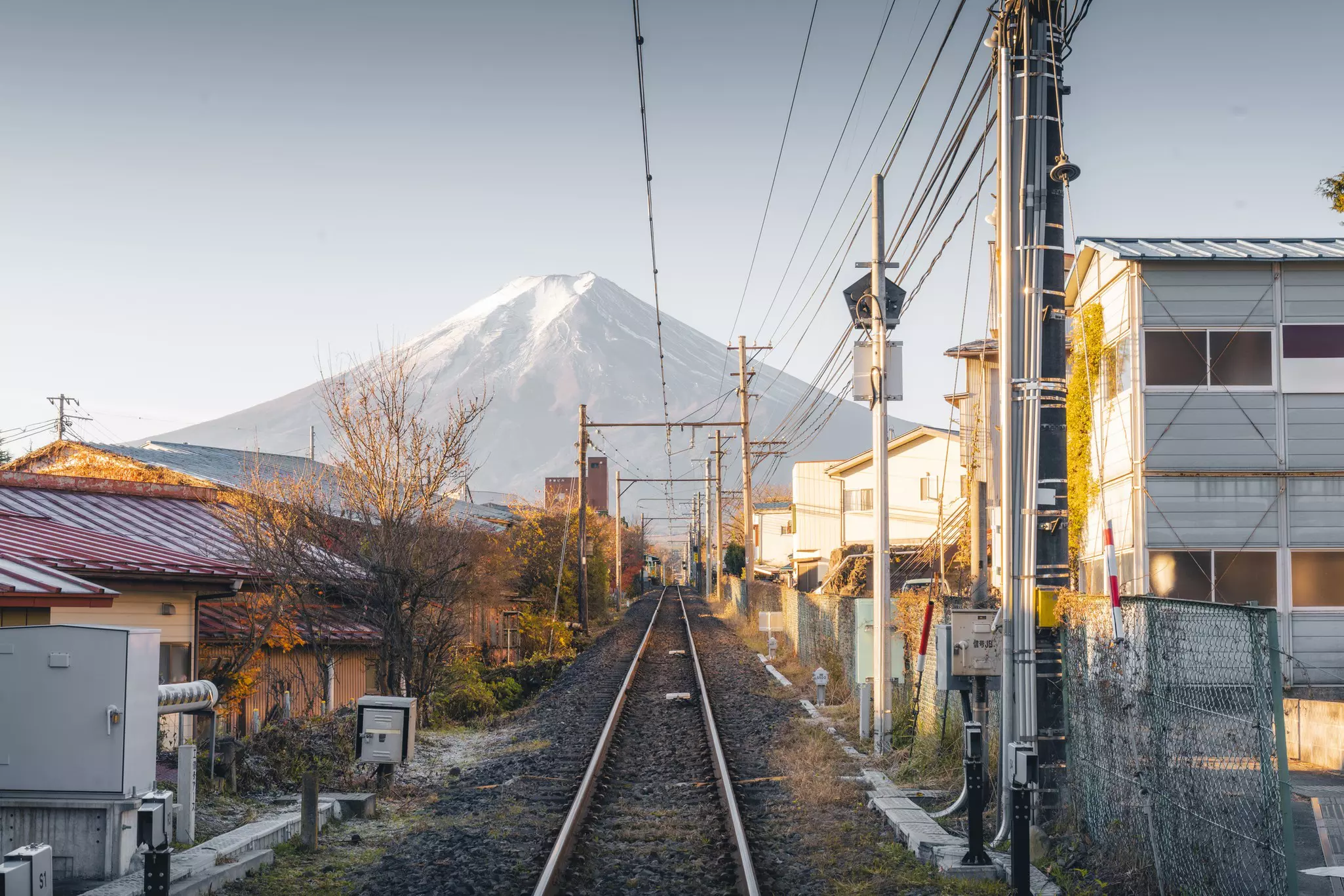 A single-track train line heading towards the iconic profile of Mount Fuji.