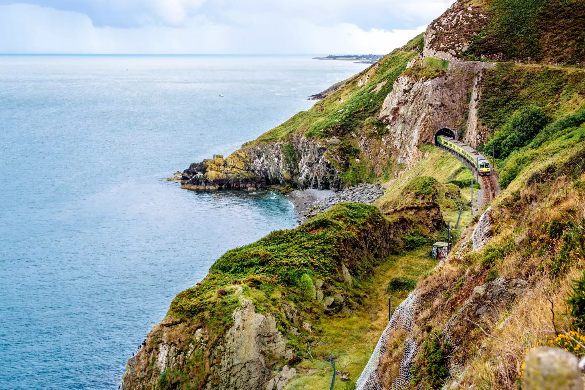 A train passes cliffs by the sea between Cliff Walk Bray and Greystones, Ireland.