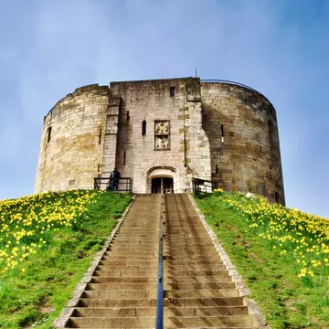 York, United Kingdom - October 2, 2016: View of Clifford's Tower, a Norman Motte and Bailey castle in York, England, with visitors climbing the steps to see the attraction.