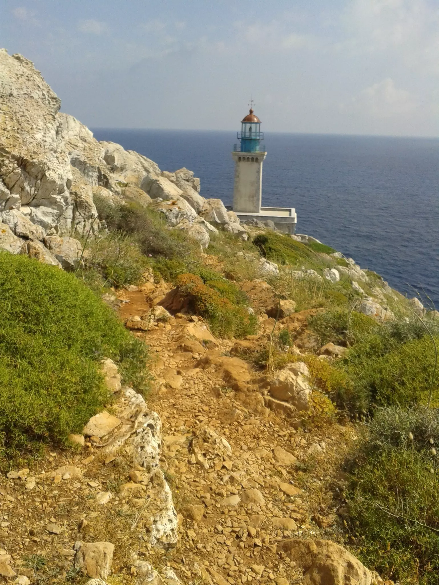 A stone lighthouse sits on the rocky cliffs in the Mani Peninsula