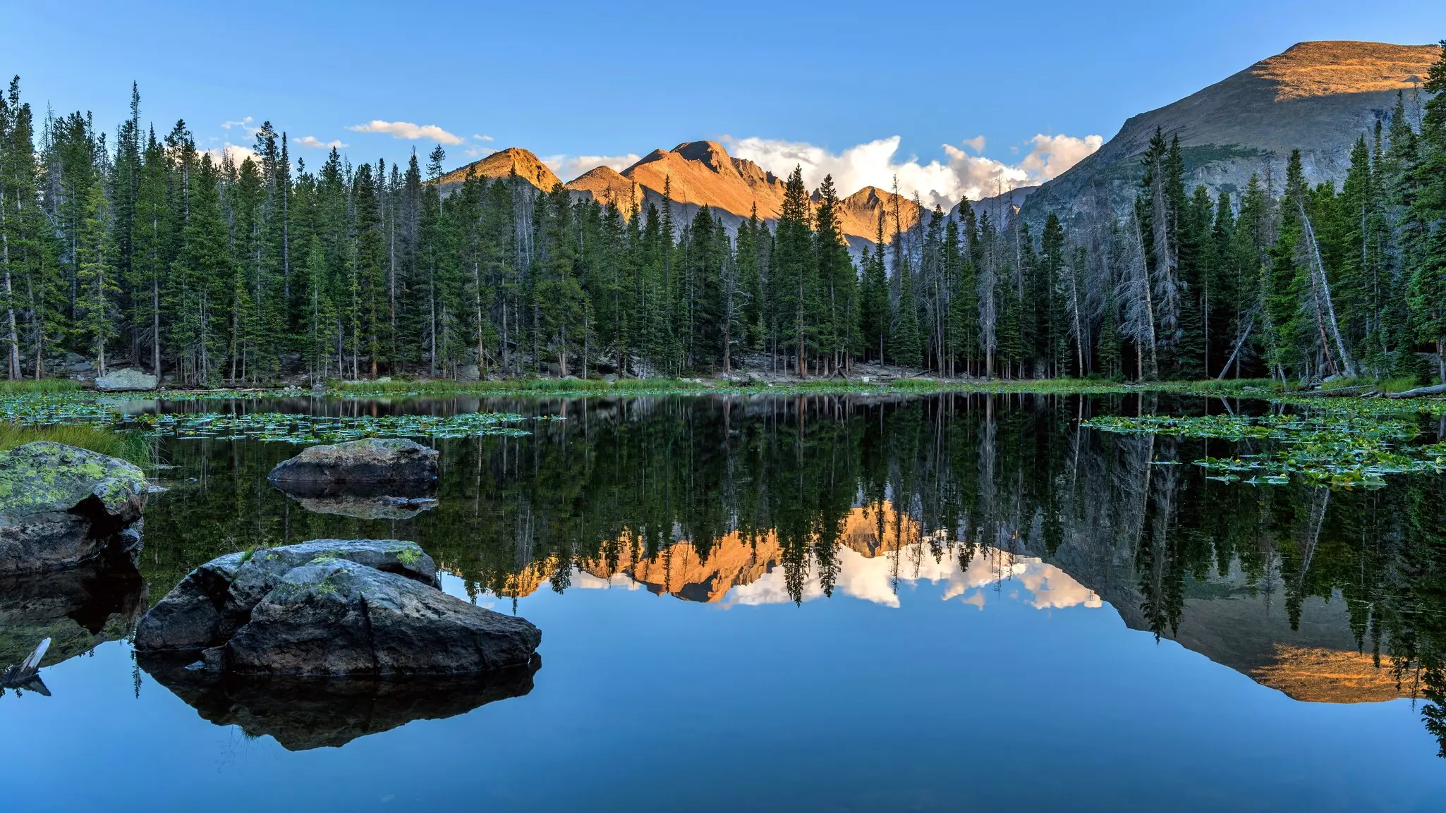 Image of lake with reddish mountains in the distance and reflected in the lake water.
