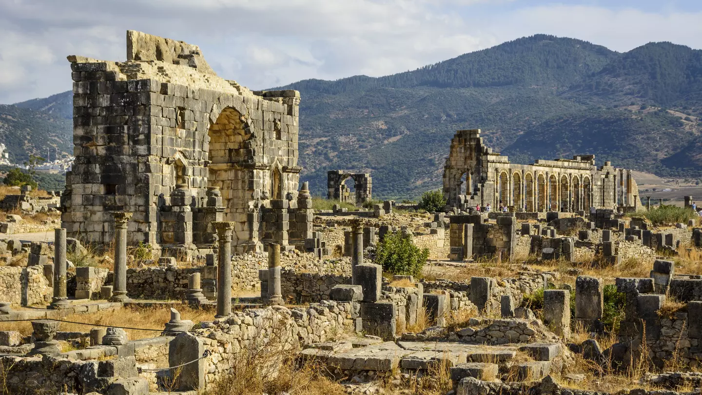 Volubilis - partly excavated Roman city near Meknes, Morocco, with mountains in the background
