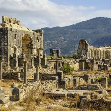 Volubilis - partly excavated Roman city near Meknes, Morocco, with mountains in the background