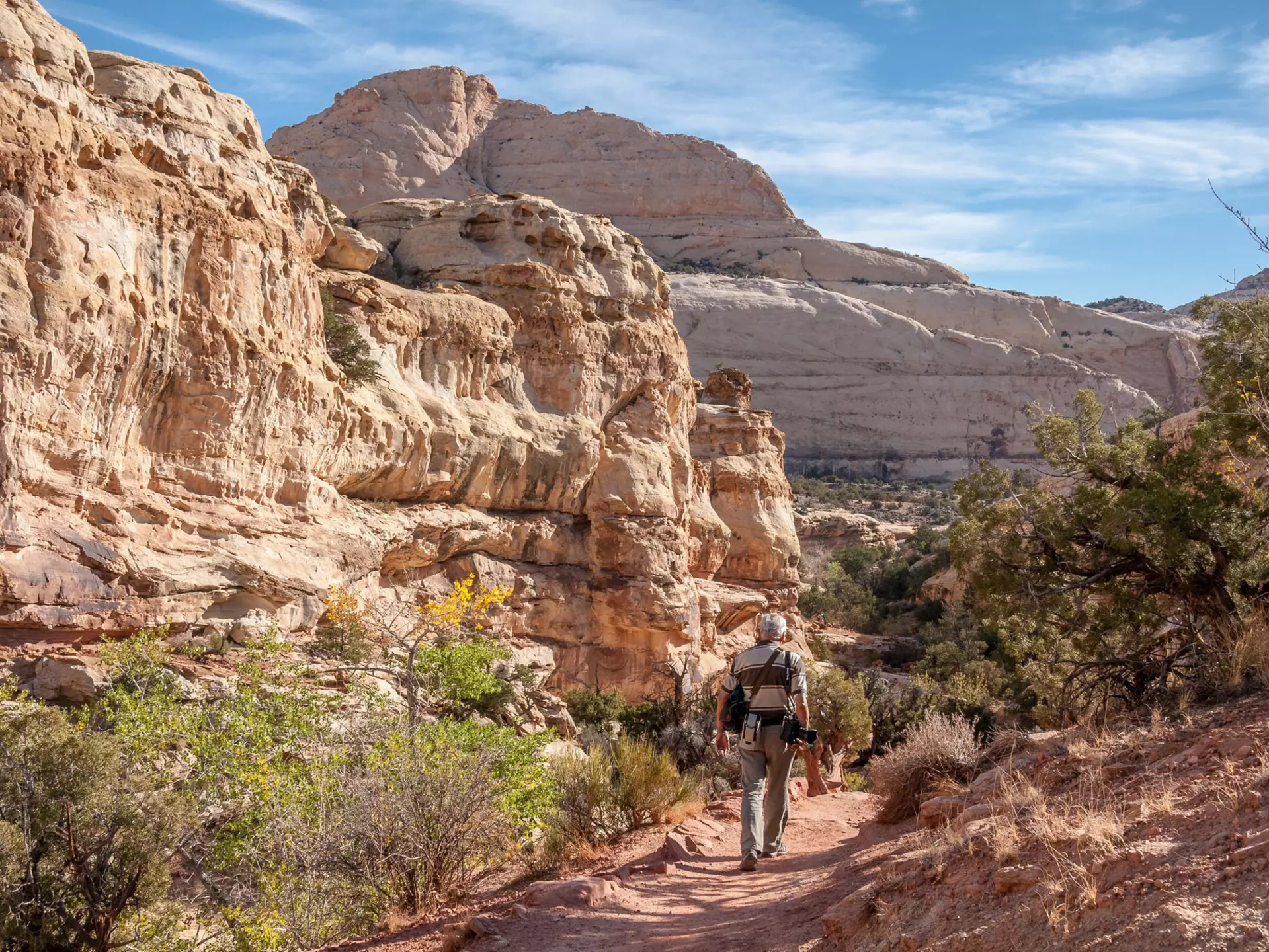 A photographer walking down a rocky path, with rock formations in the background