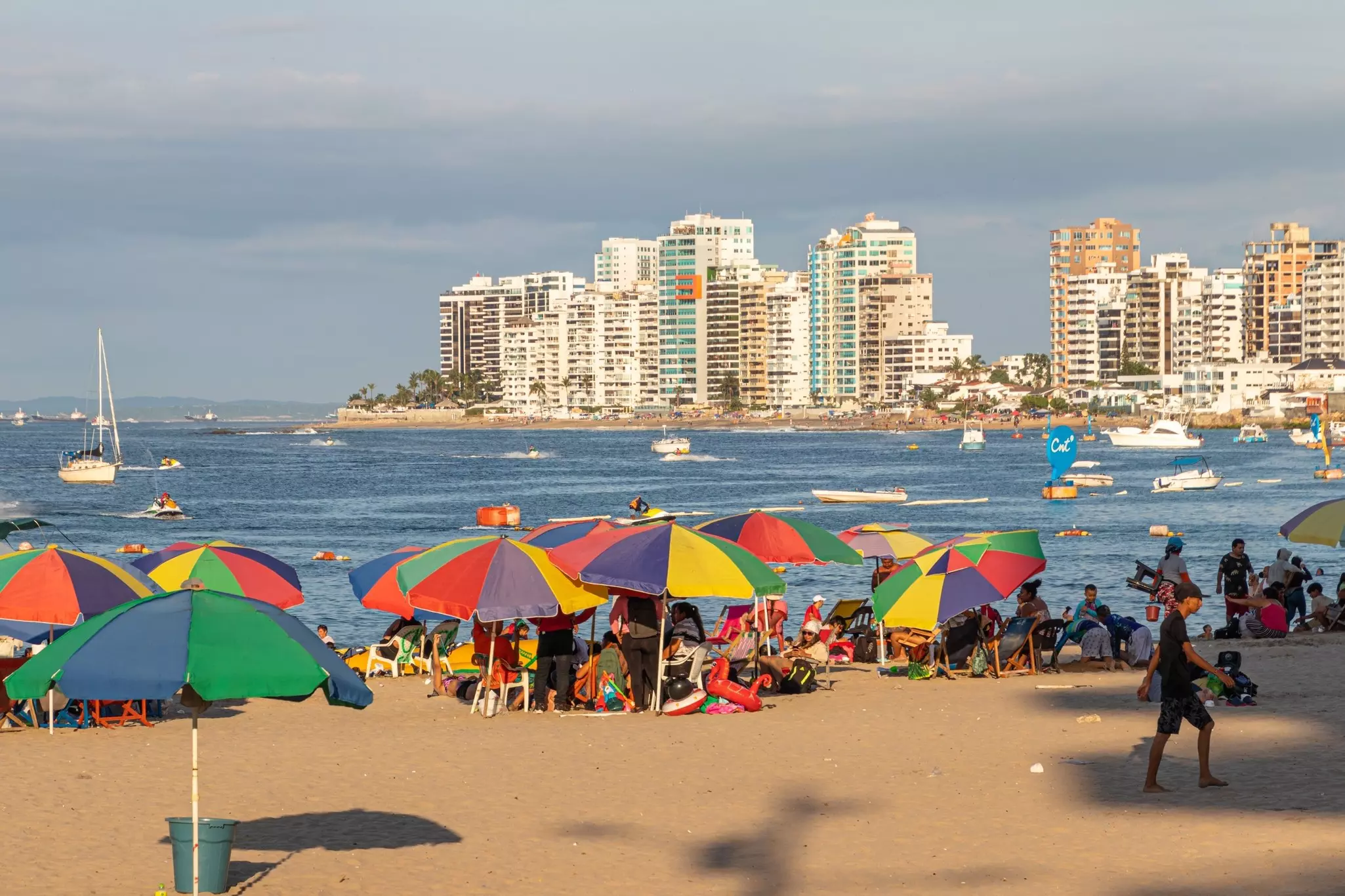 People enjoying the time at the beach in Salinas with view at modern apartment buildings along the beach. Pacific Coast, Ecuador