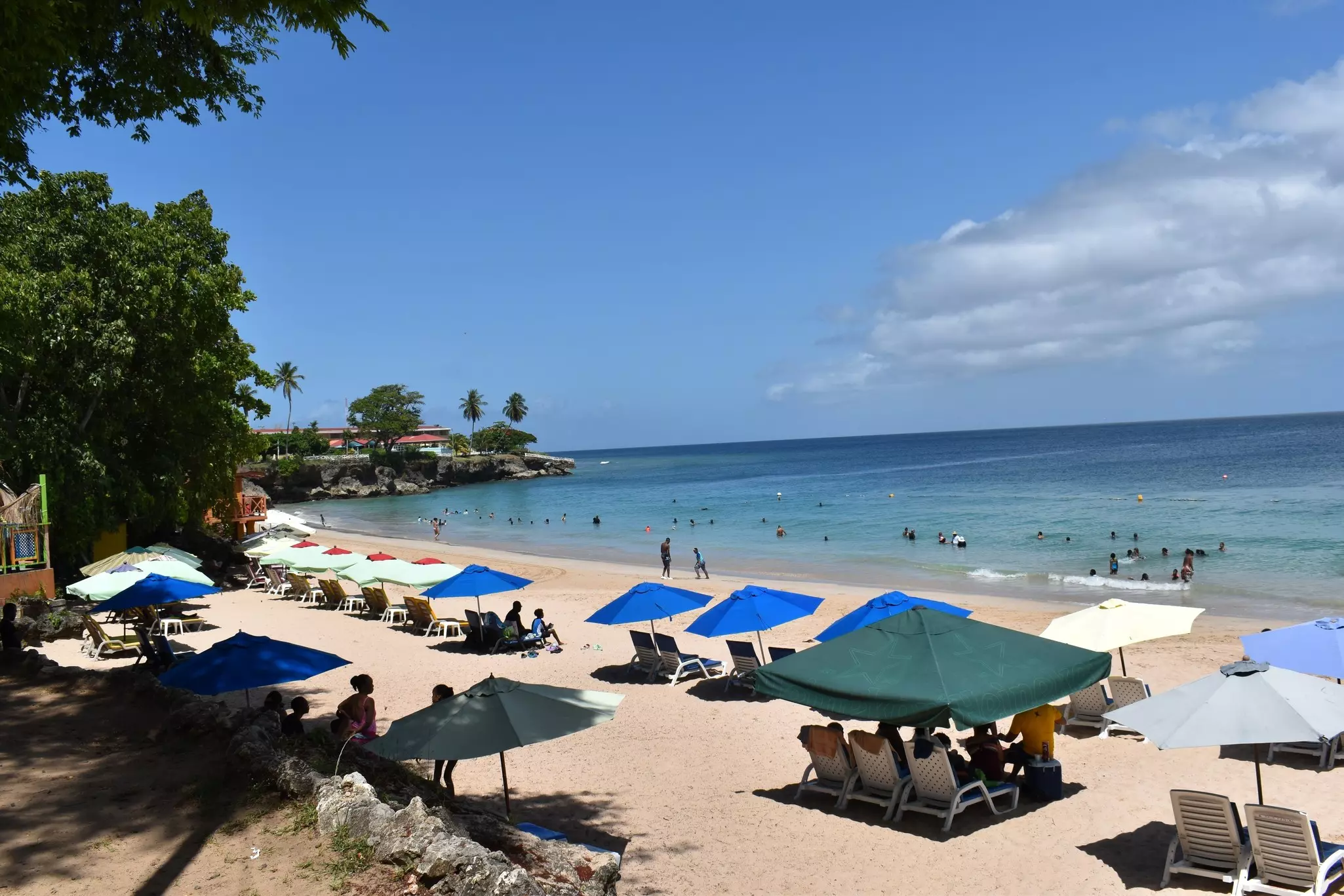 Crown Point, Tobago. Umbrellas and Beach Chairs Line the Seashore of Store Bay while Tourists and Locals Enjoy the Sunny, Summer Weather.