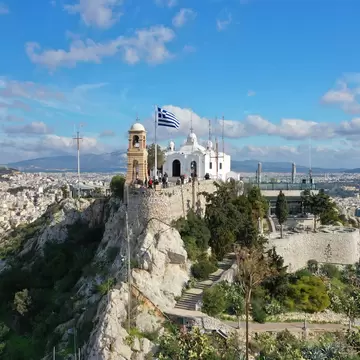 Aerial drone photo of iconic chapel of Saint George on top of Lycabettus hill with beautiful deep blue sky and clouds, Athens, Attica, Greece; Shutterstock ID 1614107947; your: Erin Lenczycki; gl: 65050; netsuite: Digital; full: POI