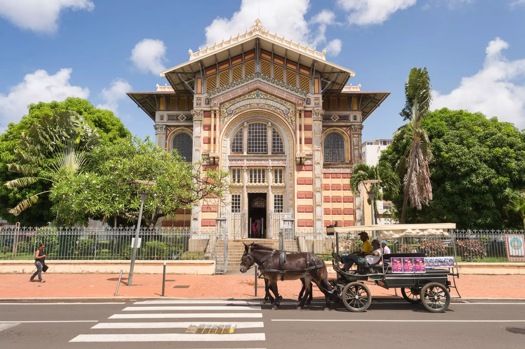 A horse-drawn carriage passing by a grand building in a city.