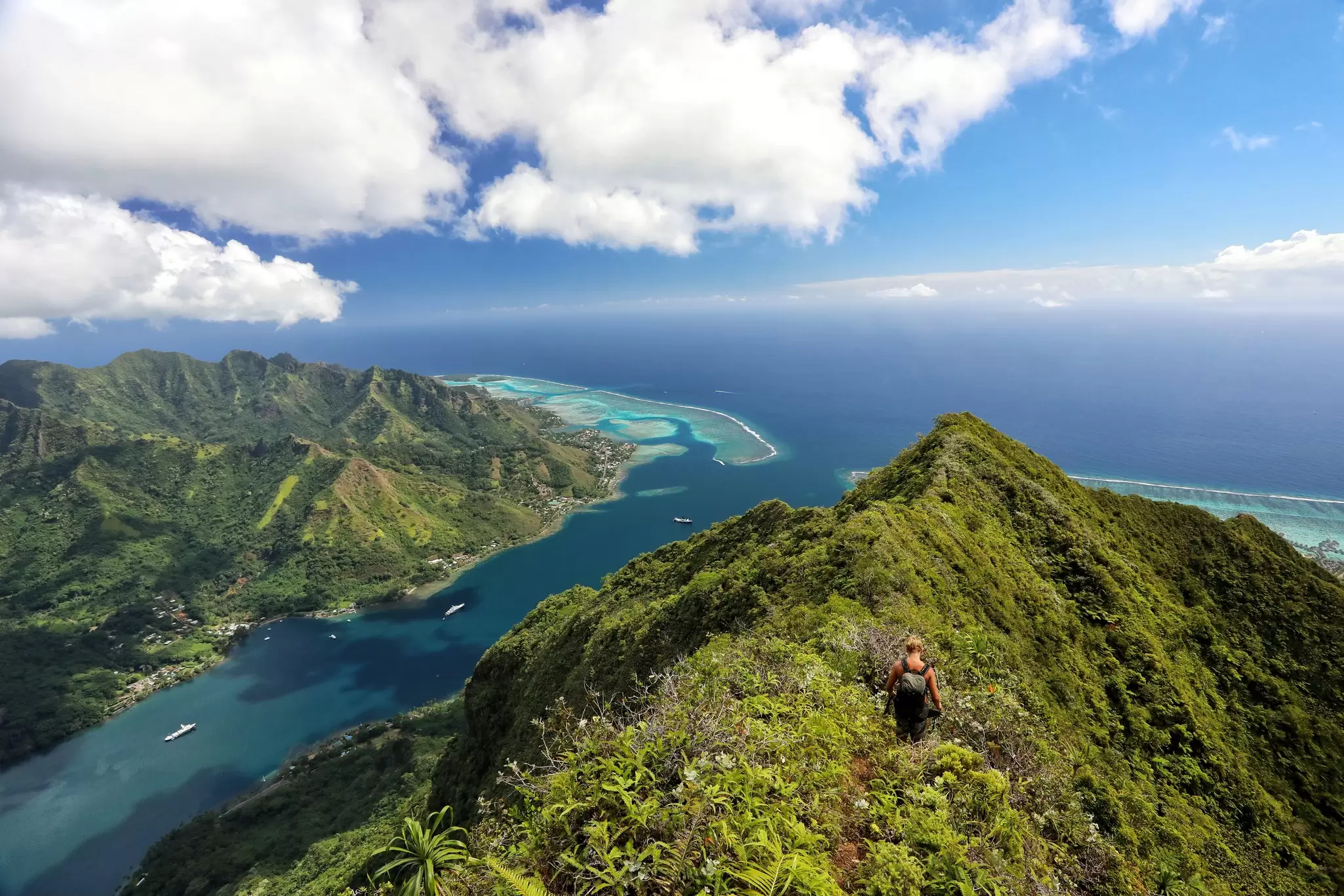 An aerial view of a hiker nearing the summit of a mountain overlooking the sea, Moʻorea, French Polynesia