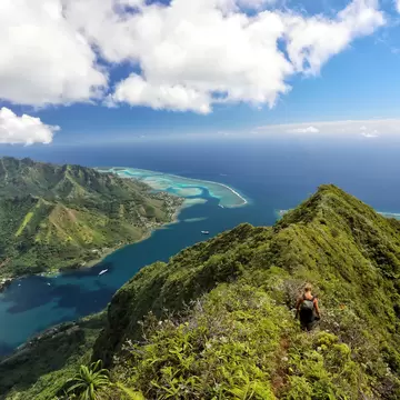 An aerial view of a hiker nearing the summit of a mountain overlooking the sea, Moʻorea, French Polynesia