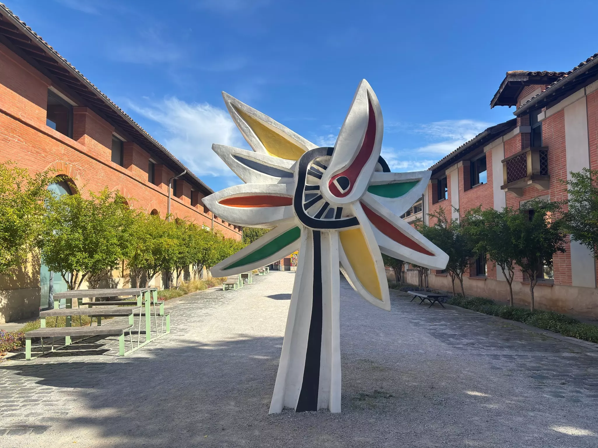 A sculpture in a courtyard with redbrick buildings on either side.