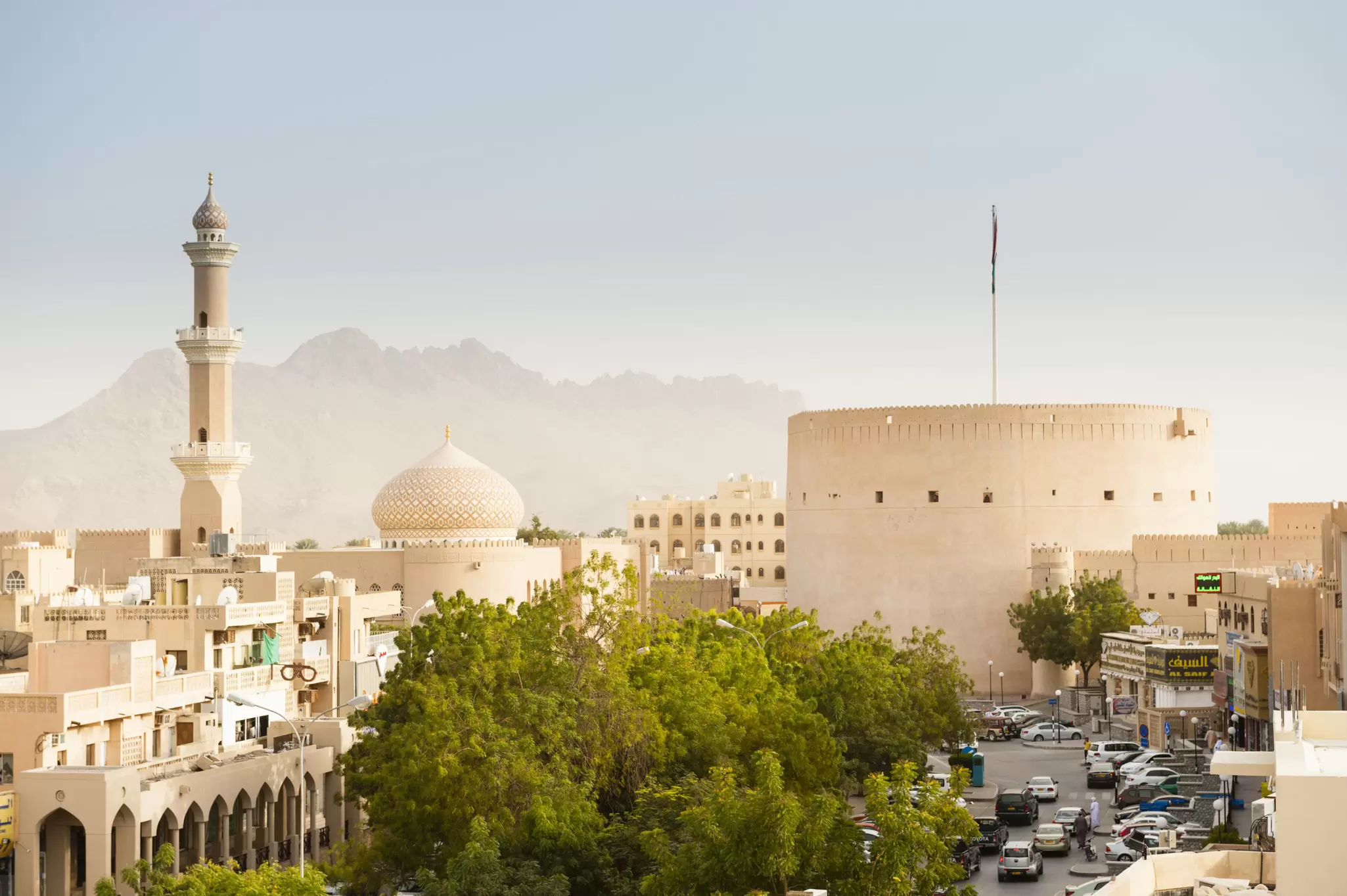 The ancient city of Nizwa in Oman, with a walled fortress and a domed mosque and minaret.