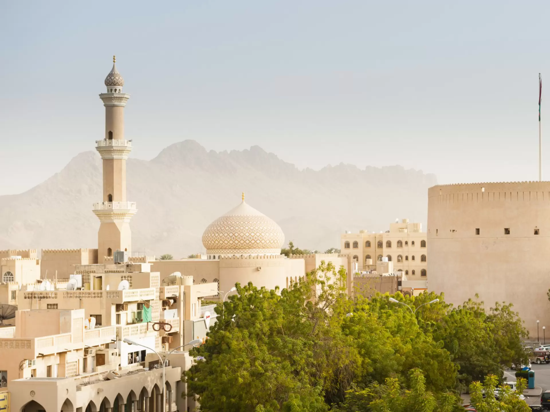 The ancient city of Nizwa in Oman, with a walled fortress and a domed mosque and minaret.