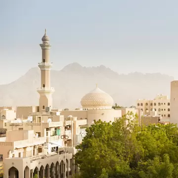 The ancient city of Nizwa in Oman, with a walled fortress and a domed mosque and minaret.