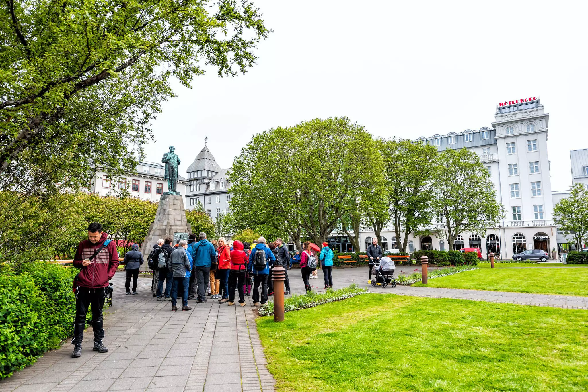 Downtown city street with Sigurdsson Statue in Austurvollur Park and tour group people