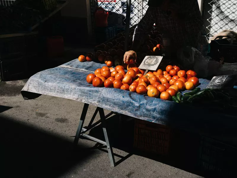 Tomatoes for sale on an outdoor table in the sunlight.