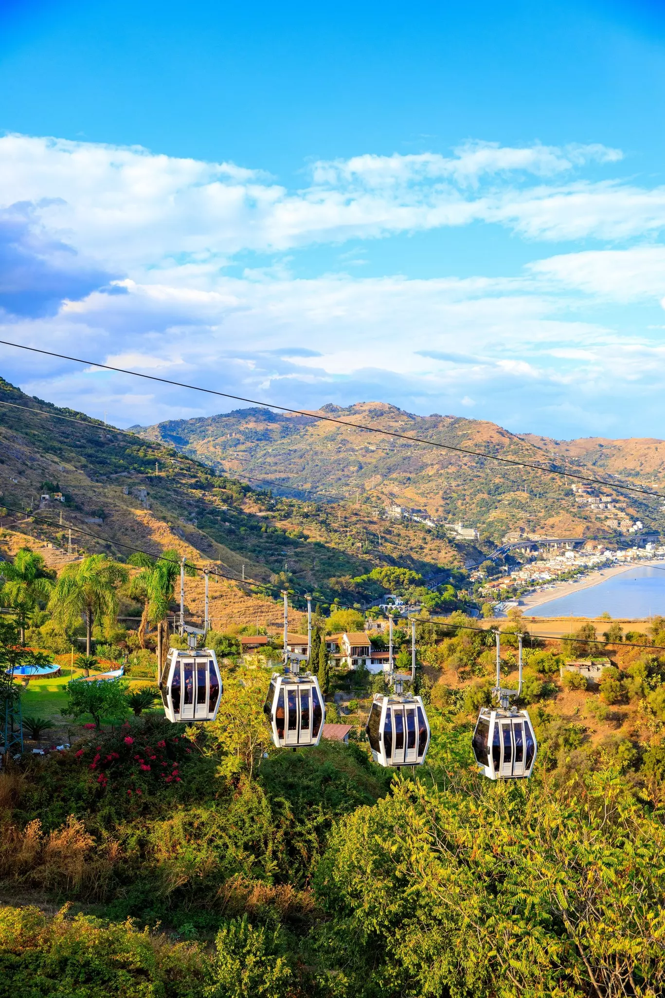Four cable cars suspended over lush terrain with mountains in the background