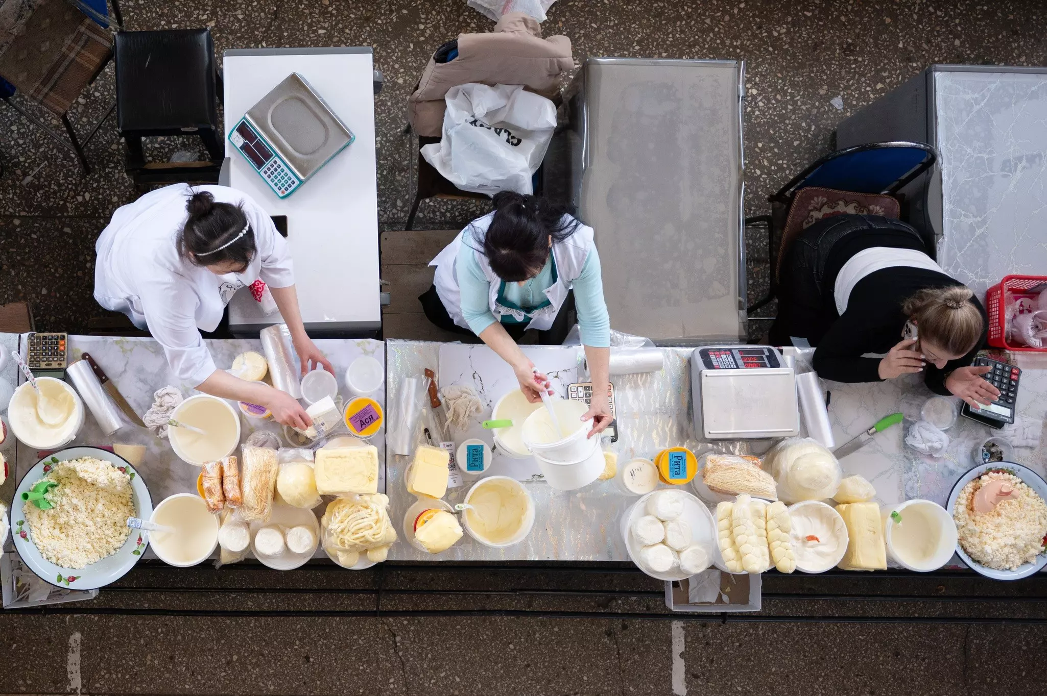 A view of three sellers of dairy products and cheese at the Green Bazaar, a market hall in Almaty, Kazakhstan