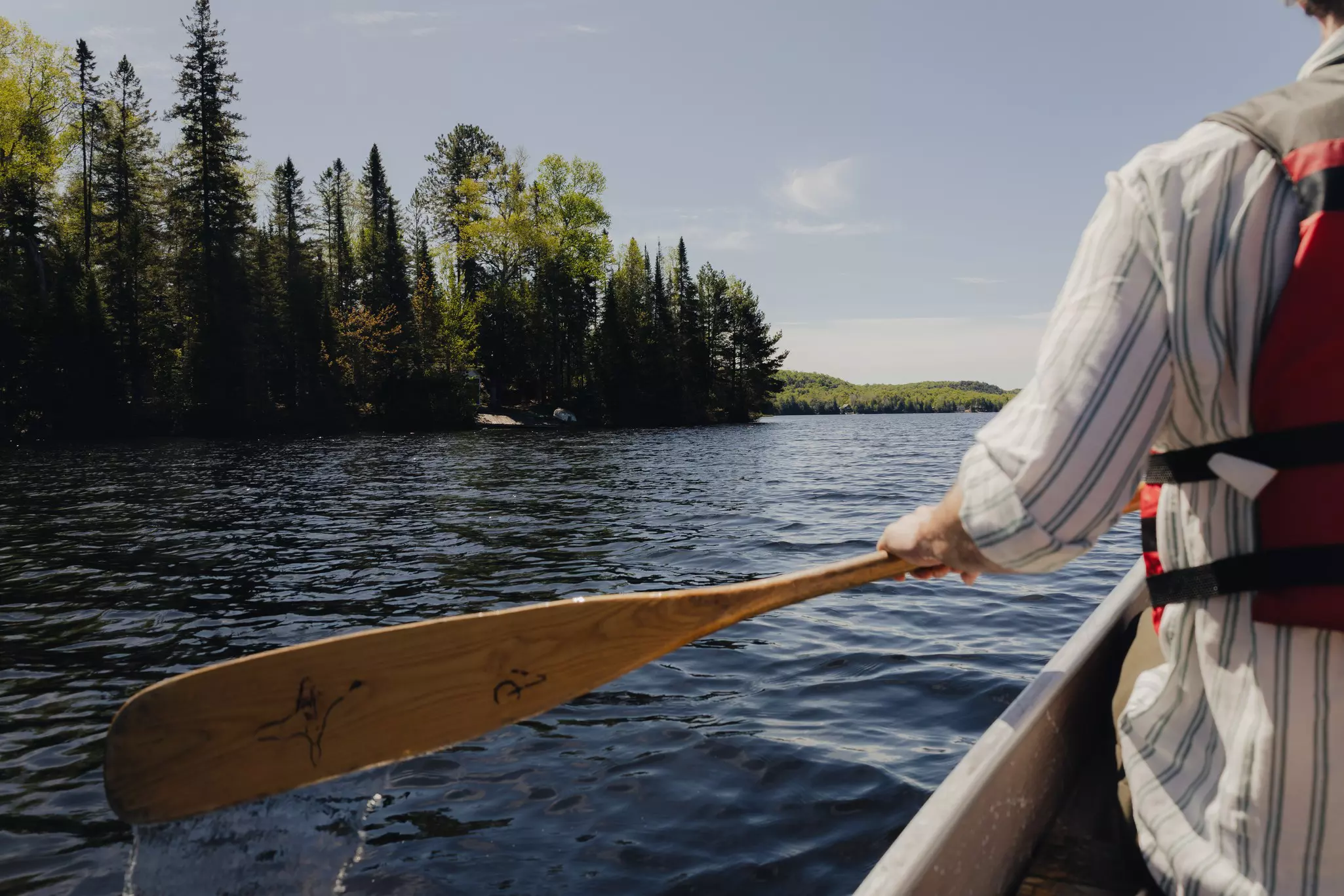 A man holding an paddle as he canoes on a lake.