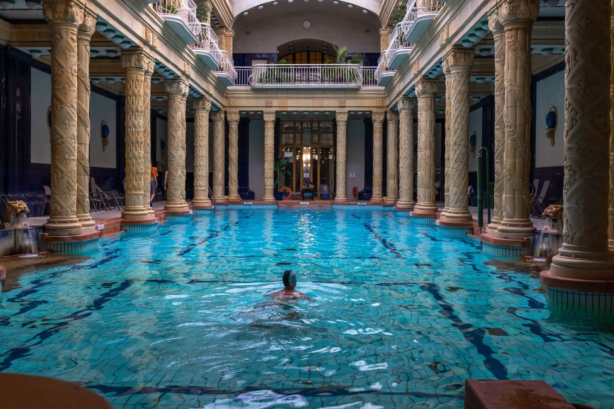 One person in a large thermal pool surrounded by columns.