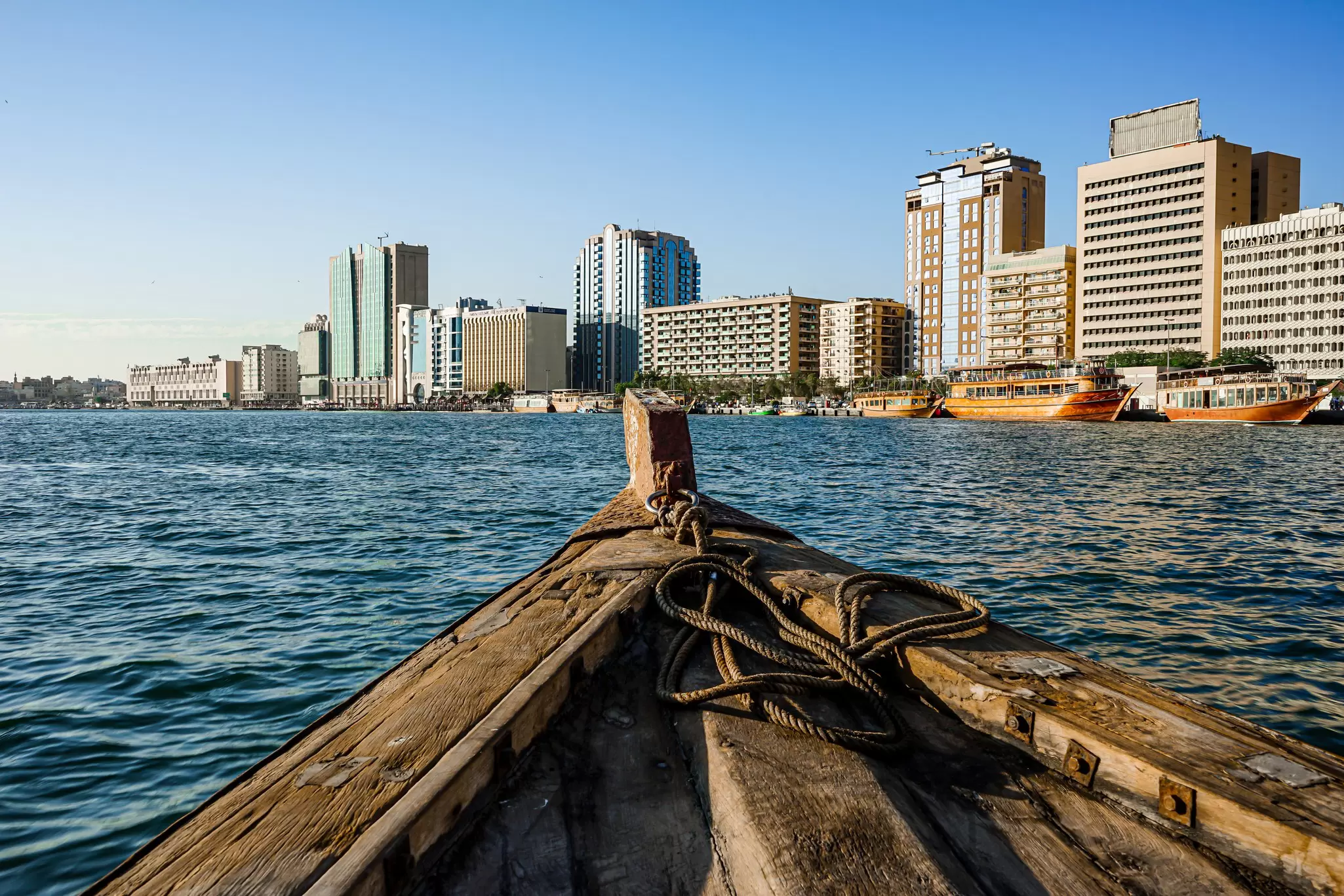A small wooden boat on a channel in front of some medium-rise waterfront buikdings: Old Deira Creek, Dubai