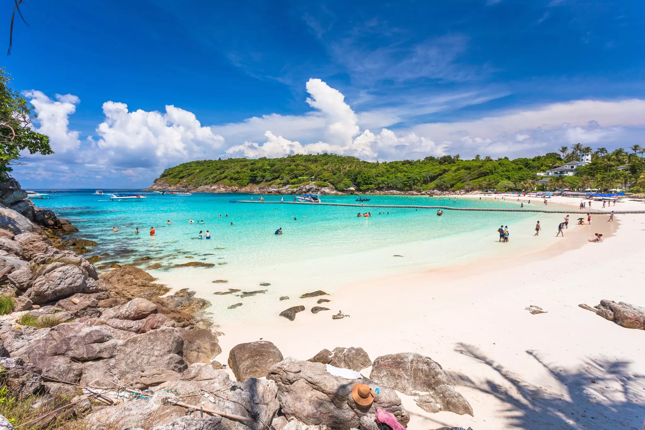 People swim in the shallow turquoise waters off a white-sand beach.