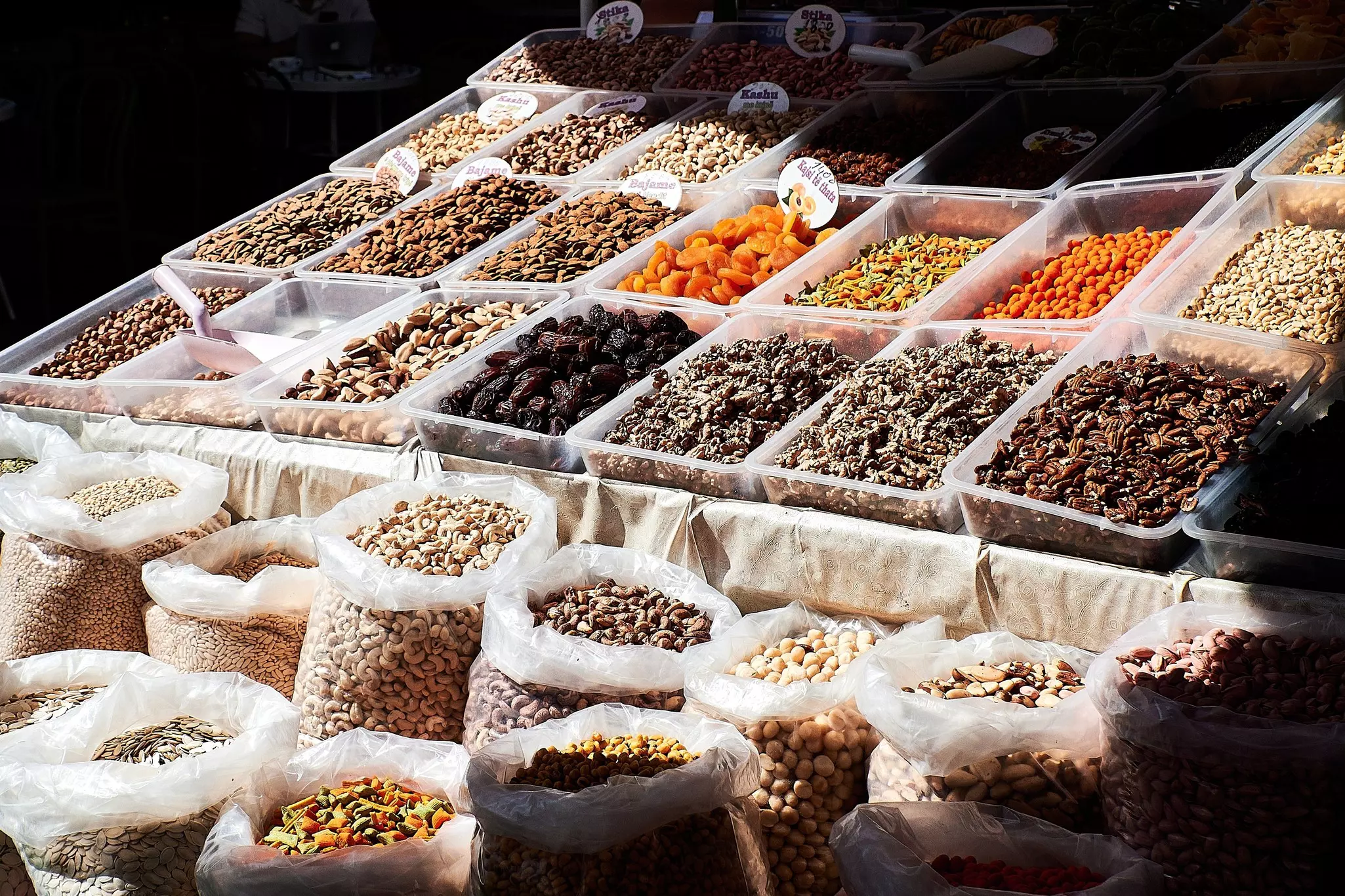 Bins of dried fruits and spices are arranged at a market.