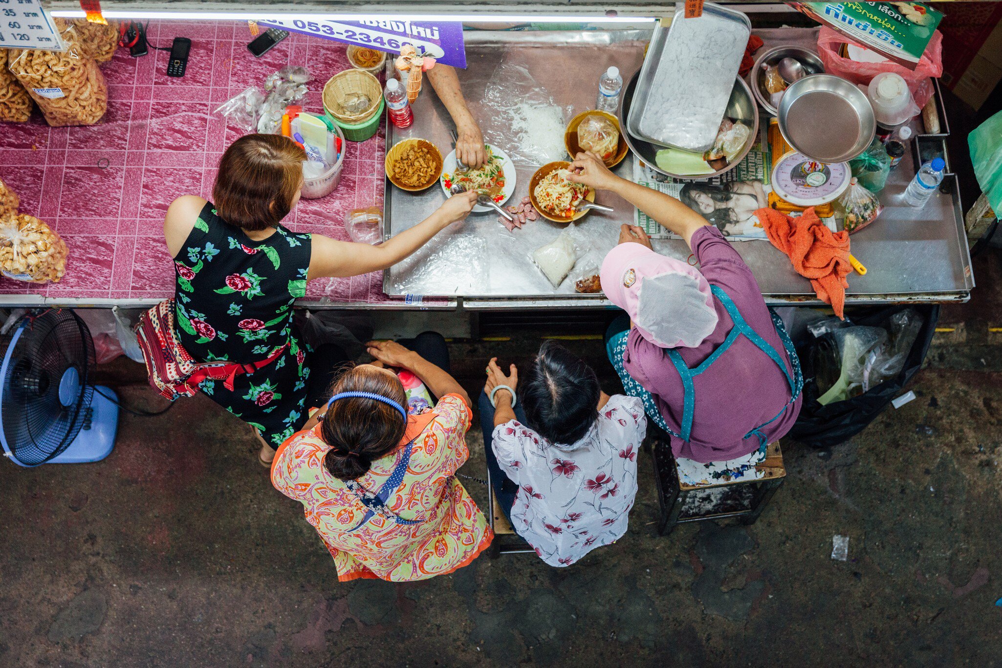 Overhead shot of a group eating Thai food for lunch at the Warorot market in Chiang Mai, Thailand.