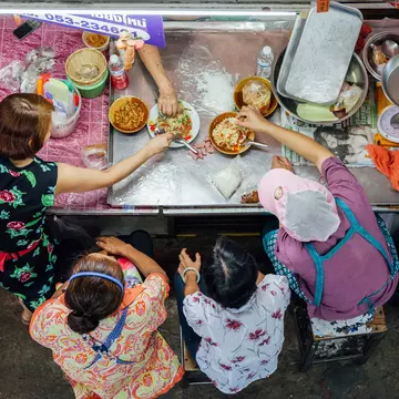 Overhead shot of a group eating Thai food for lunch at the Warorot market in Chiang Mai, Thailand.