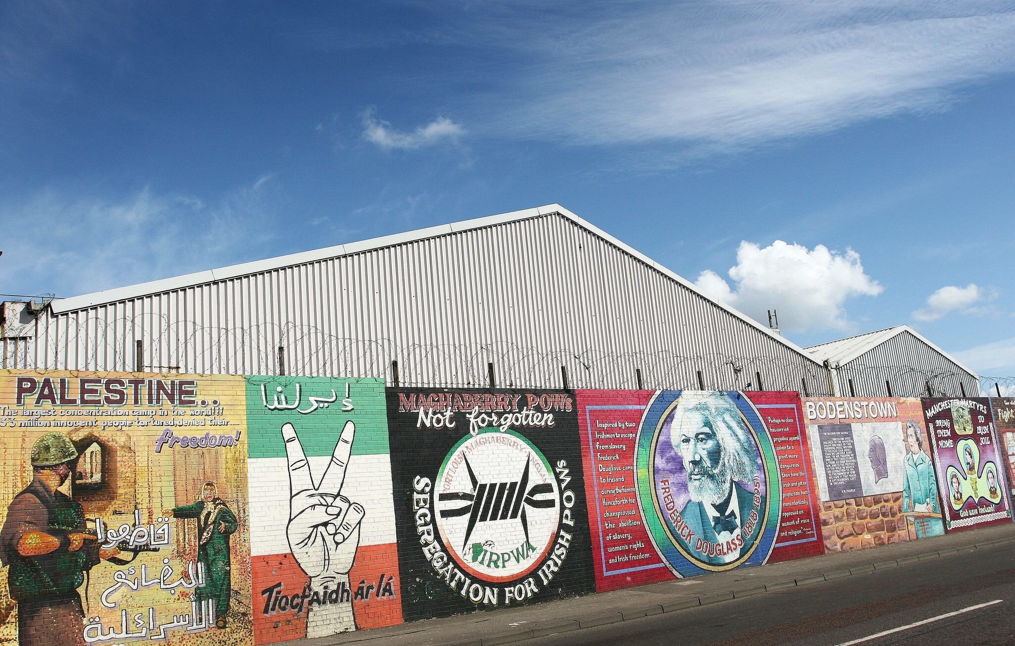 Falls Road Murals on the Falls Road. Belfast, Ireland. A row of political murals against the barbed-wire dividing wall. 
